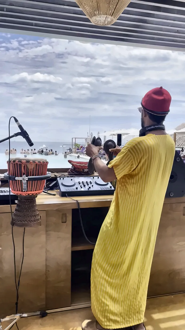 Taïb in a yellow djellaba playing over a pool full of people