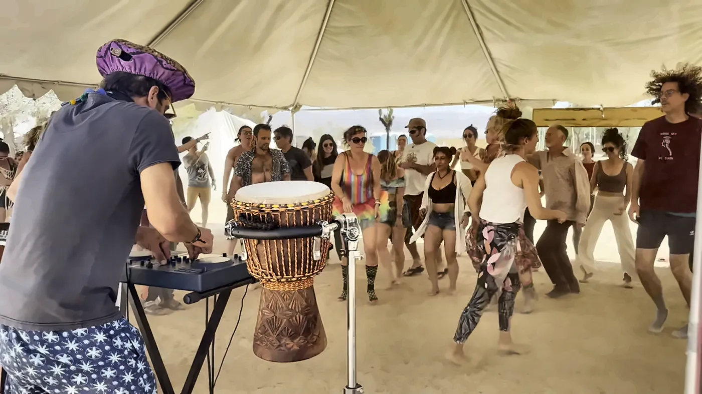 Taïb on the decks and djembe while a tent full of people dances on the sand