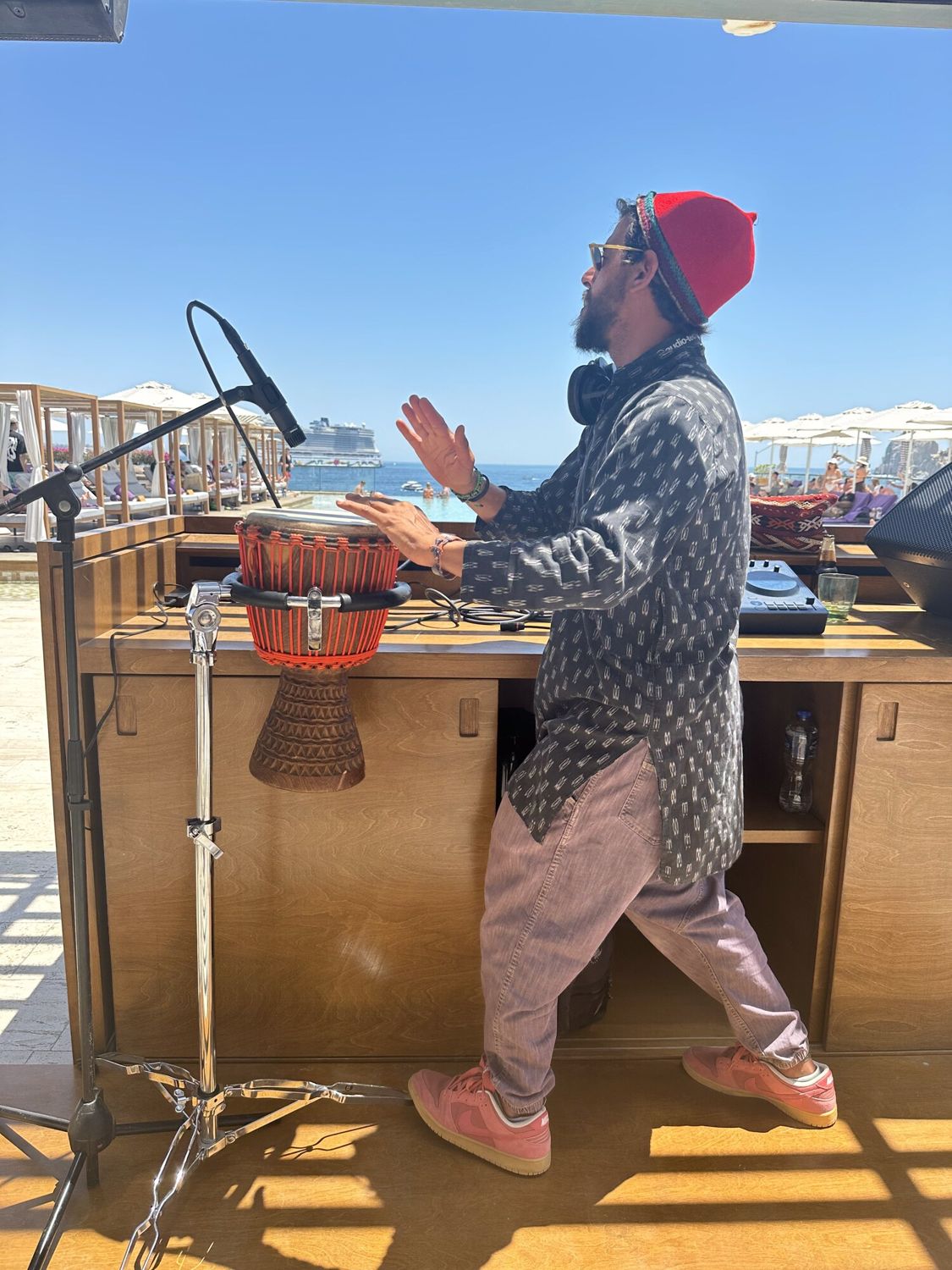 Taïb drumming at the Breathless booth, sea behind him
