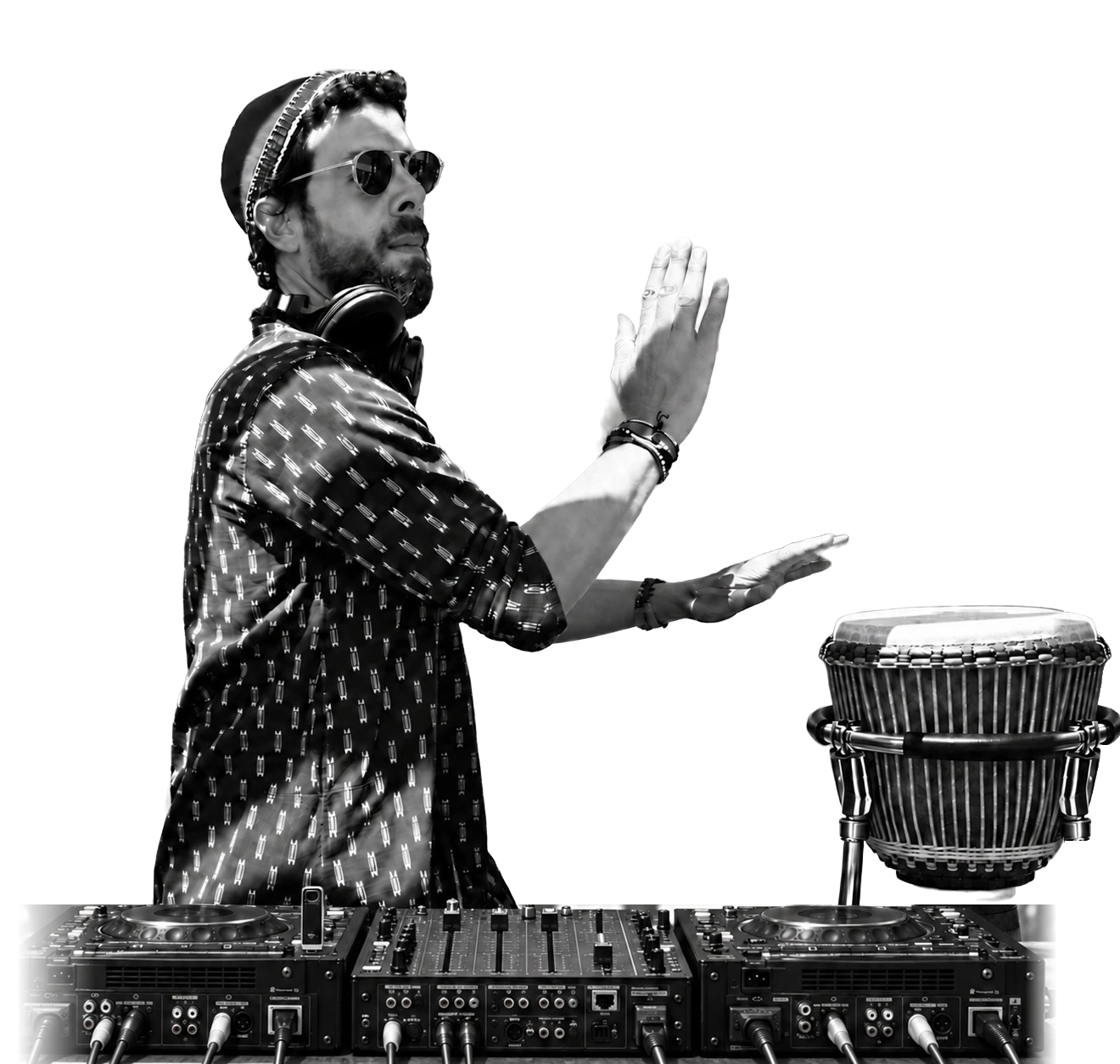 Taïb in his hat and headphones, playing a djembe on its stand behind two Pioneer CDJ-3000s and a mixer